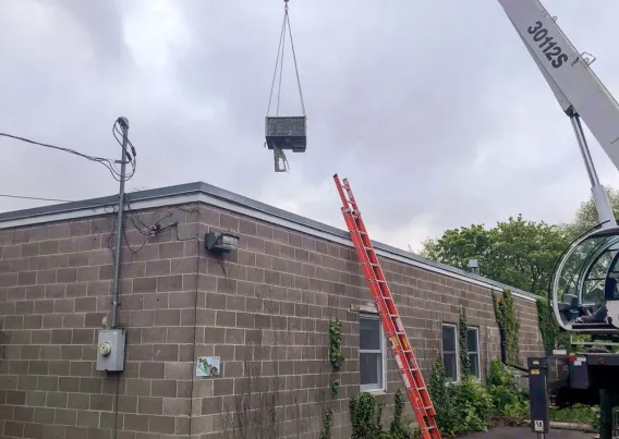 A crane placing a RTU on on top of a building. 