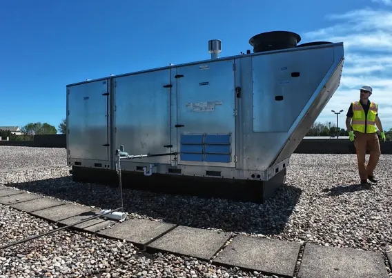A contractor walking around a HVAC unit. 