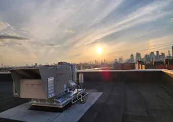 Two Daikin Rebel dual fuel heat pump rooftop units installed on a commercial building roof in Queens, New York
